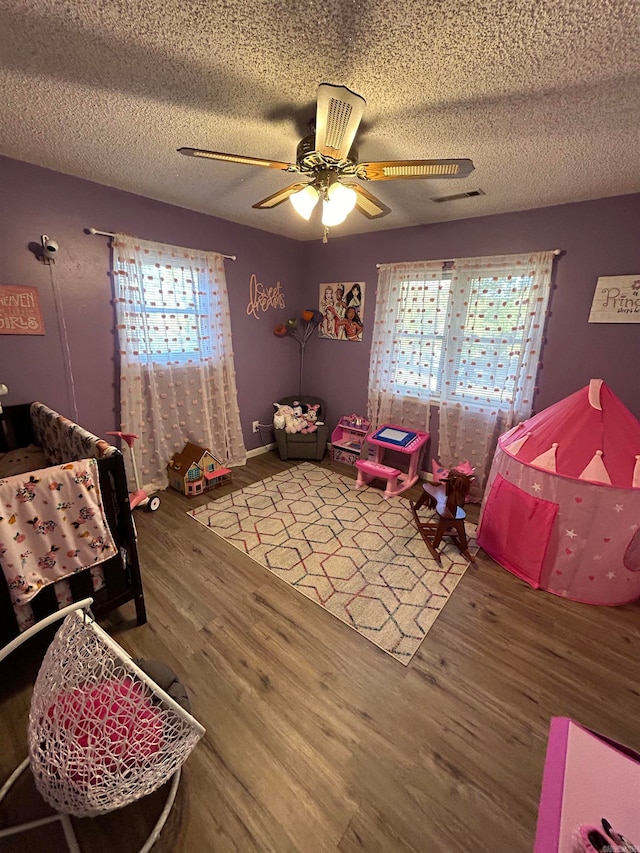 bedroom with a textured ceiling, wood-type flooring, and ceiling fan