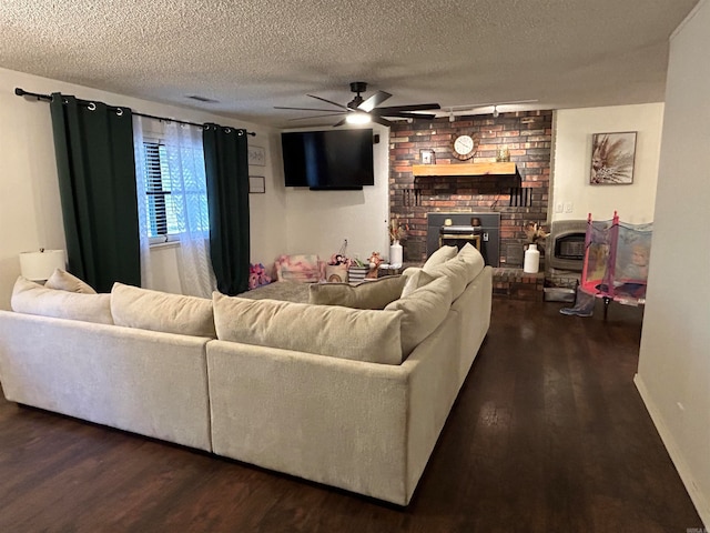 living room with a textured ceiling, a fireplace, dark hardwood / wood-style floors, and ceiling fan