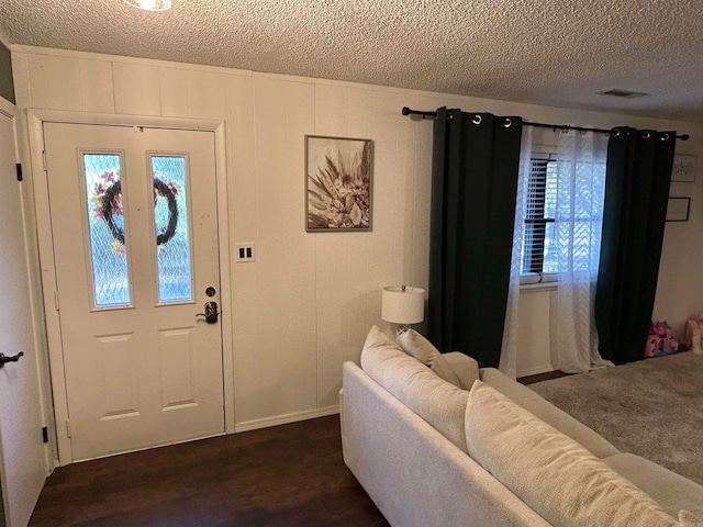 foyer entrance with a textured ceiling and dark hardwood / wood-style floors