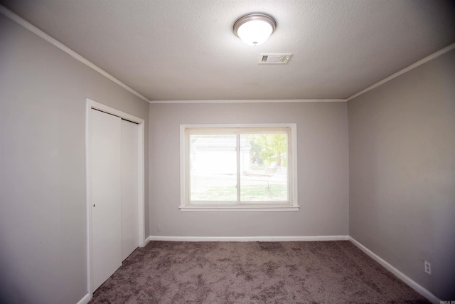 spare room featuring crown molding, a textured ceiling, and dark colored carpet