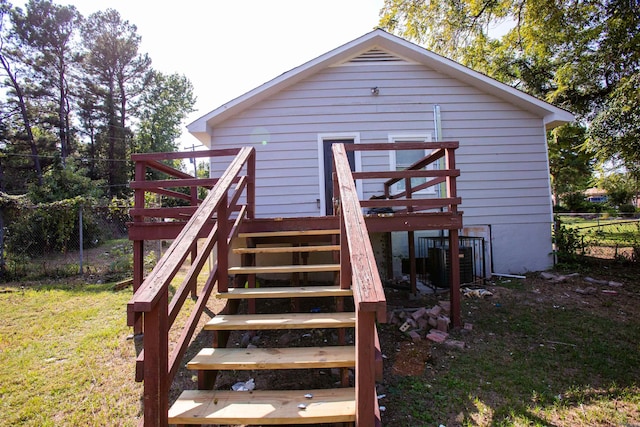 rear view of house featuring a wooden deck, cooling unit, and a yard