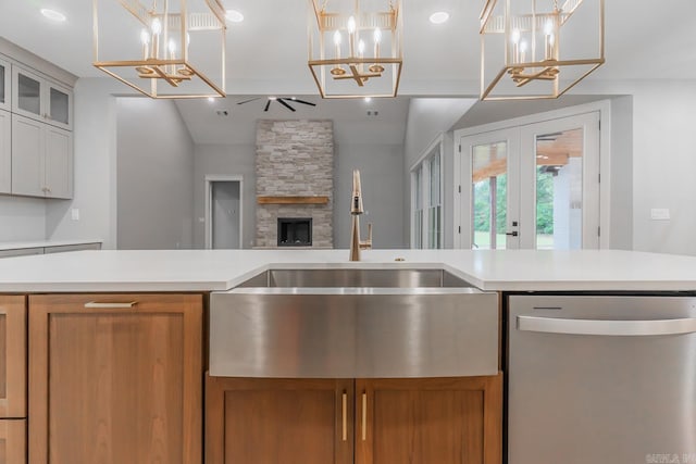 kitchen featuring dishwasher, white cabinetry, decorative light fixtures, and a fireplace