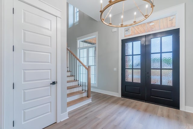 entrance foyer featuring a chandelier, light wood-type flooring, and french doors