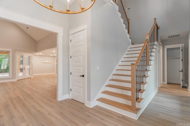 stairway featuring wood-type flooring, an inviting chandelier, and high vaulted ceiling