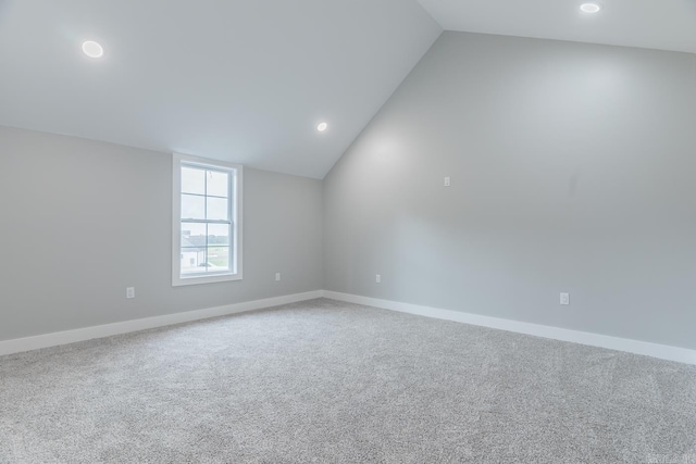 spare room featuring carpet and vaulted ceiling