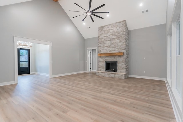 unfurnished living room with high vaulted ceiling, light hardwood / wood-style floors, a fireplace, and ceiling fan with notable chandelier