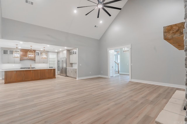 unfurnished living room featuring high vaulted ceiling, light wood-type flooring, sink, and ceiling fan