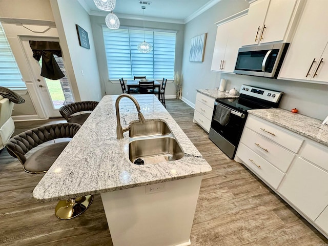 kitchen featuring stainless steel appliances, sink, a breakfast bar area, white cabinets, and pendant lighting