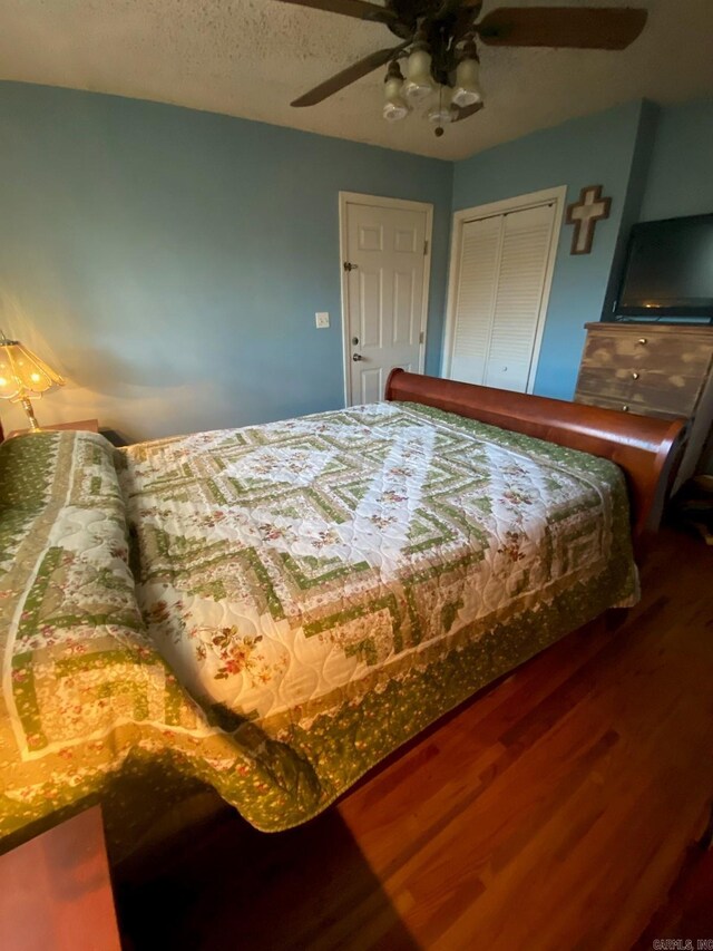 bedroom with hardwood / wood-style floors, a textured ceiling, a closet, and ceiling fan