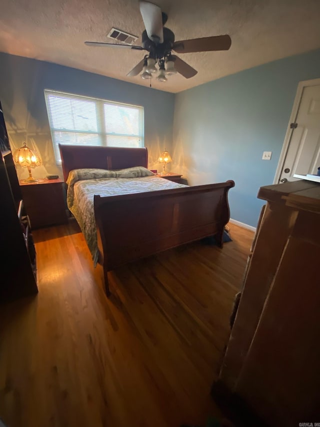 bedroom featuring ceiling fan, light hardwood / wood-style flooring, and a textured ceiling