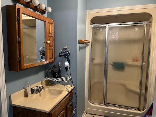 bathroom featuring tile patterned flooring, vanity, and a shower with shower door