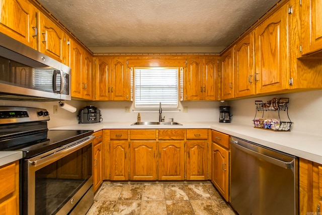 kitchen featuring a textured ceiling, stainless steel appliances, and sink