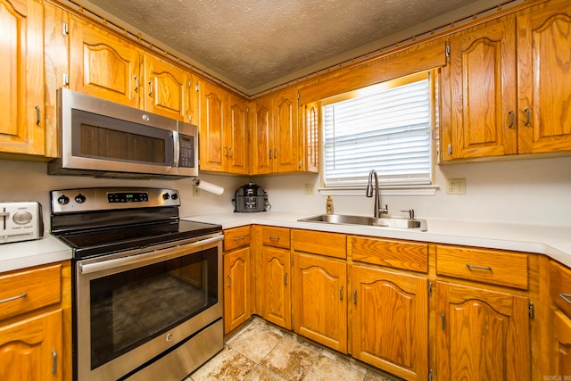 kitchen with sink, appliances with stainless steel finishes, and a textured ceiling