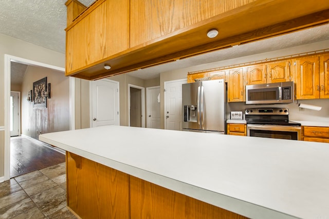 kitchen with a textured ceiling, hardwood / wood-style flooring, and stainless steel appliances