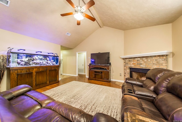 living room featuring lofted ceiling, ceiling fan, a textured ceiling, wood-type flooring, and a fireplace