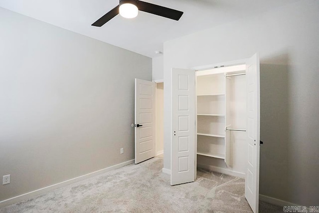 unfurnished bedroom featuring a spacious closet, light carpet, a closet, and ceiling fan