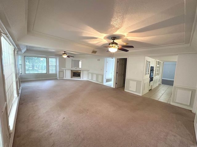 unfurnished living room featuring light carpet, a tray ceiling, and ceiling fan