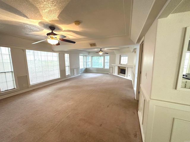 unfurnished living room featuring ceiling fan, a wealth of natural light, and light colored carpet