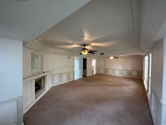 unfurnished living room featuring ceiling fan, carpet, and a wealth of natural light