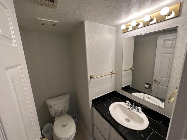 bathroom featuring toilet, a textured ceiling, vanity, and tile patterned flooring