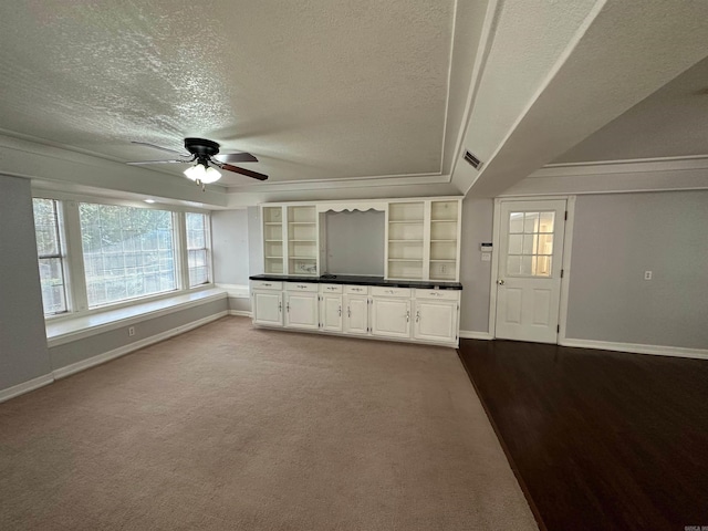 unfurnished living room featuring carpet, crown molding, a textured ceiling, and ceiling fan