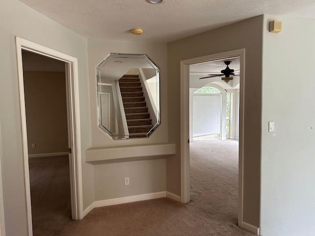 hall with a textured ceiling and carpet floors