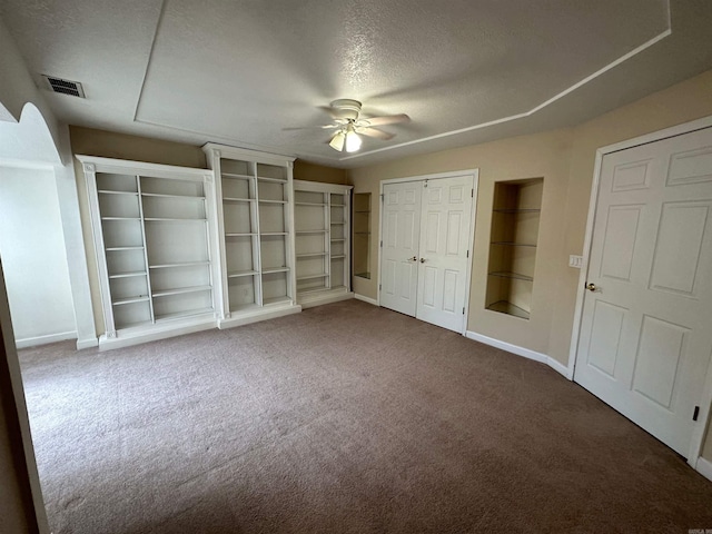 unfurnished bedroom with carpet floors, multiple closets, a textured ceiling, and ceiling fan