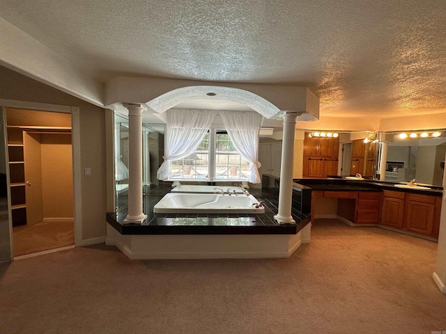 unfurnished bedroom with decorative columns, a textured ceiling, and light colored carpet