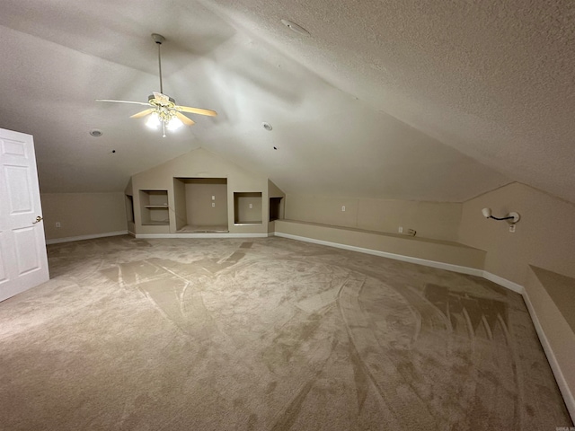 additional living space with ceiling fan, a textured ceiling, carpet, and vaulted ceiling