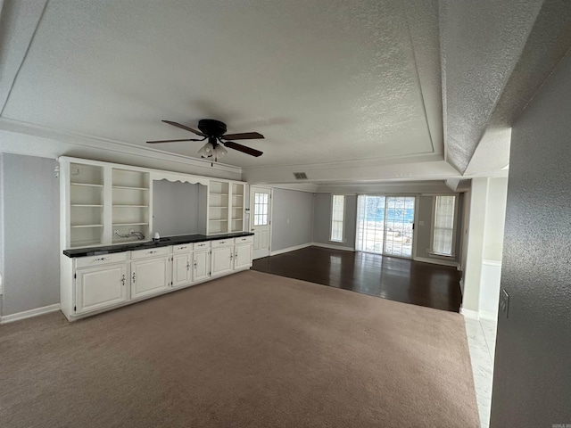 unfurnished living room featuring built in features, a textured ceiling, carpet floors, and ceiling fan