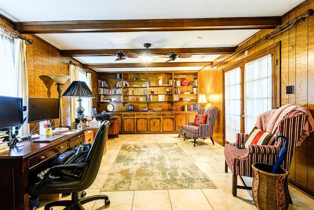 office area featuring ceiling fan, beamed ceiling, a textured ceiling, and wooden walls