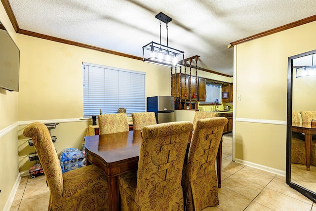 tiled dining area with sink, a textured ceiling, and ornamental molding