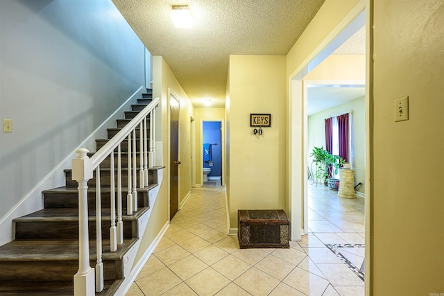 hallway featuring a textured ceiling and light tile patterned floors