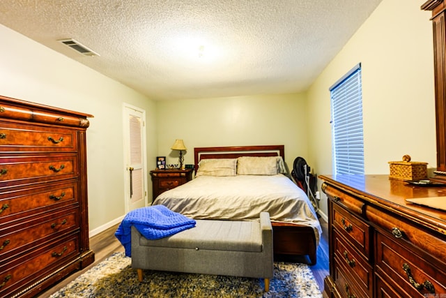 bedroom with a closet, wood-type flooring, and a textured ceiling