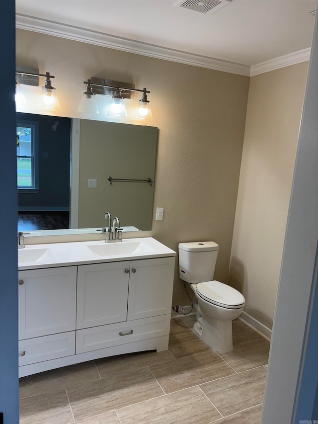 bathroom with ornamental molding, vanity, and toilet