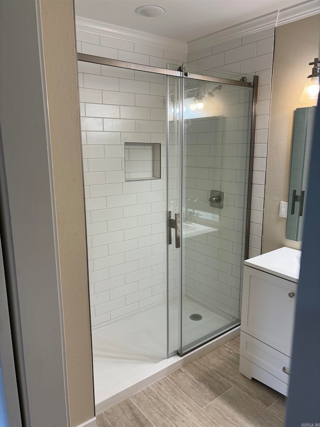 bathroom featuring vanity, ornamental molding, and a shower with shower door