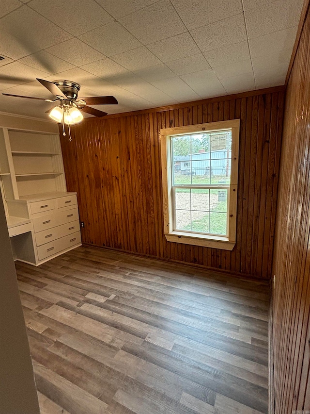 unfurnished bedroom featuring wooden walls, hardwood / wood-style floors, and ceiling fan