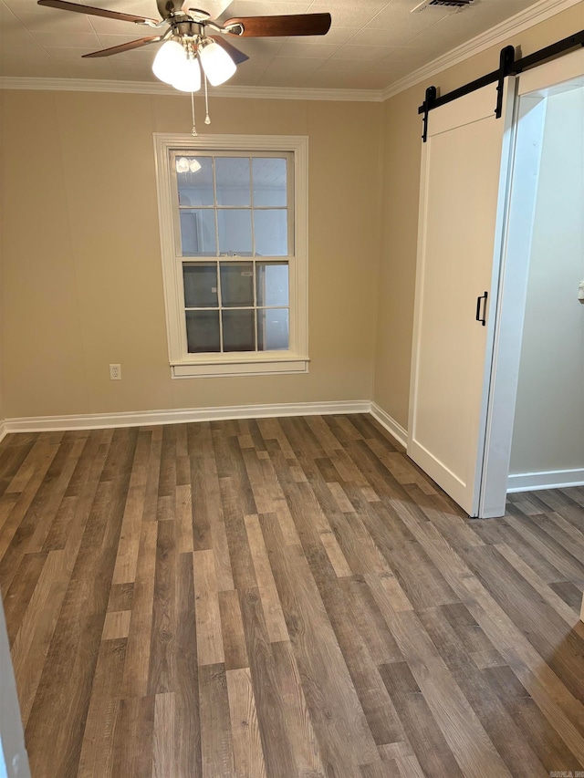 unfurnished room with a barn door, ceiling fan, ornamental molding, and hardwood / wood-style floors