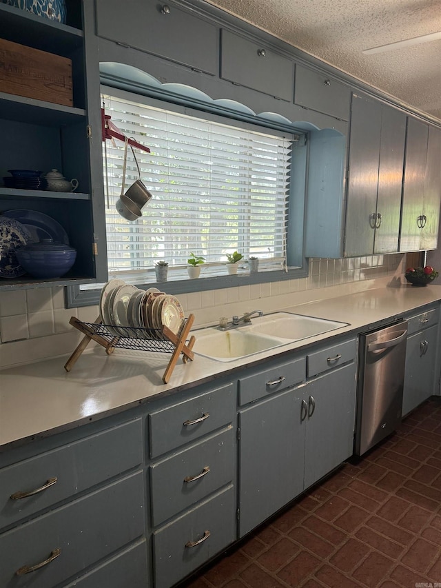 kitchen featuring a textured ceiling, decorative backsplash, stainless steel dishwasher, and gray cabinetry