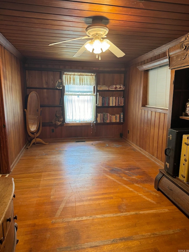 empty room featuring hardwood / wood-style floors, ceiling fan, wood walls, and wood ceiling