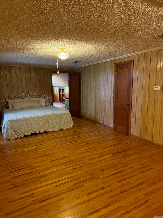 unfurnished bedroom featuring wood-type flooring, wooden walls, and a textured ceiling