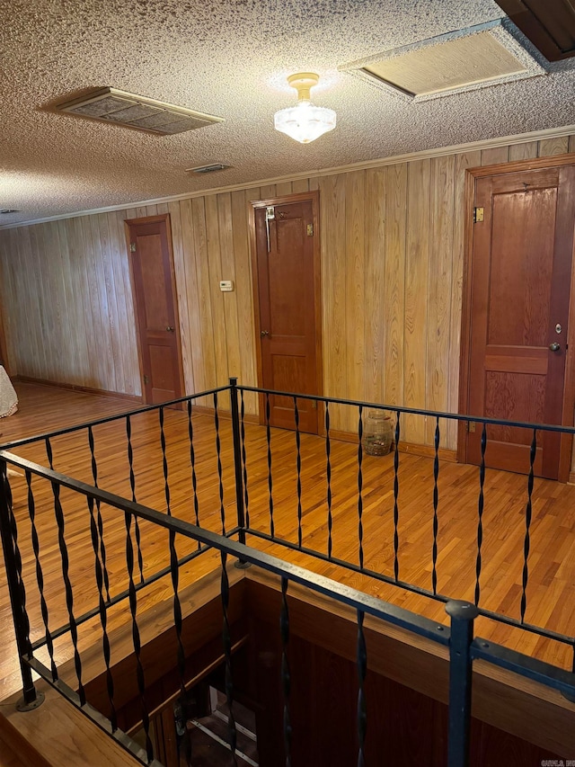 staircase with hardwood / wood-style floors, a textured ceiling, and wooden walls