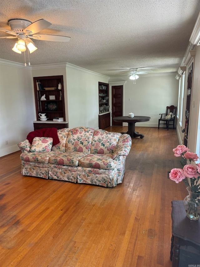 living room with a textured ceiling, ornamental molding, hardwood / wood-style flooring, and ceiling fan