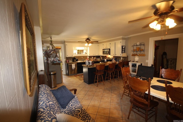 dining room with ceiling fan, light tile patterned floors, sink, and ornamental molding