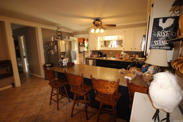 kitchen featuring white cabinetry, sink, ceiling fan, and a kitchen breakfast bar