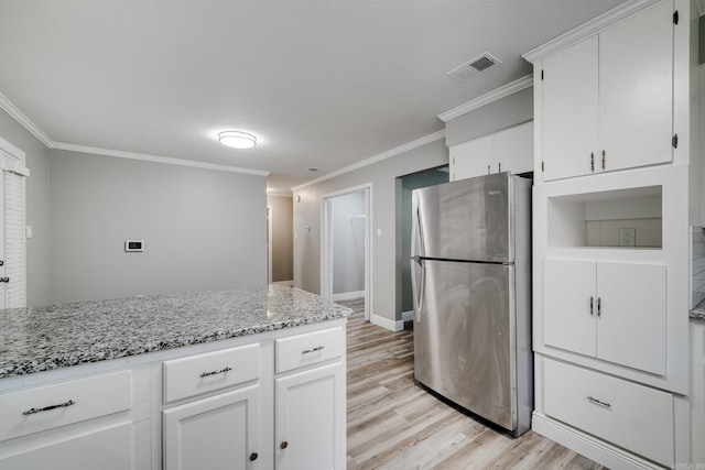 kitchen with light stone counters, ornamental molding, stainless steel refrigerator, light hardwood / wood-style floors, and white cabinets