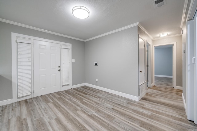 foyer entrance with light hardwood / wood-style floors, a textured ceiling, and ornamental molding