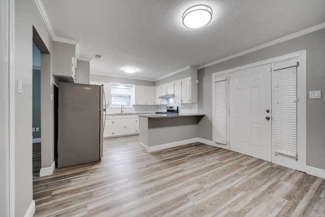 kitchen featuring stainless steel appliances, kitchen peninsula, ornamental molding, light hardwood / wood-style flooring, and white cabinets