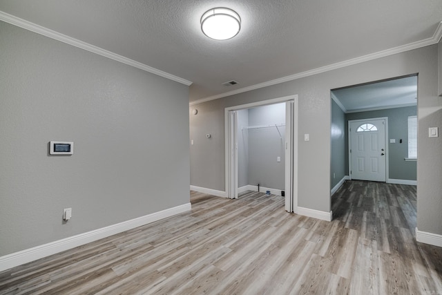 spare room with a textured ceiling, crown molding, and light hardwood / wood-style flooring