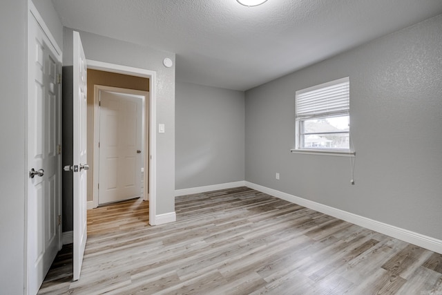 unfurnished bedroom with a closet, a textured ceiling, and light hardwood / wood-style flooring